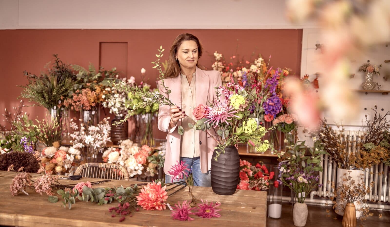 Marijke schikt een kleurrijk zijden bloemen boeket in de studio